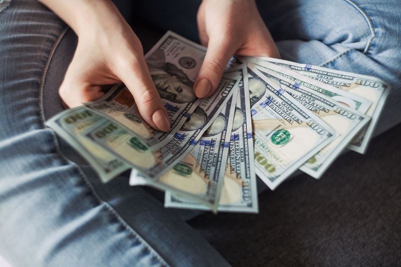 Woman's hands holding 9 one hundred dollar bills